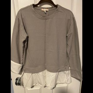 Grey sweatshirt with white cuffs and ruffle.
